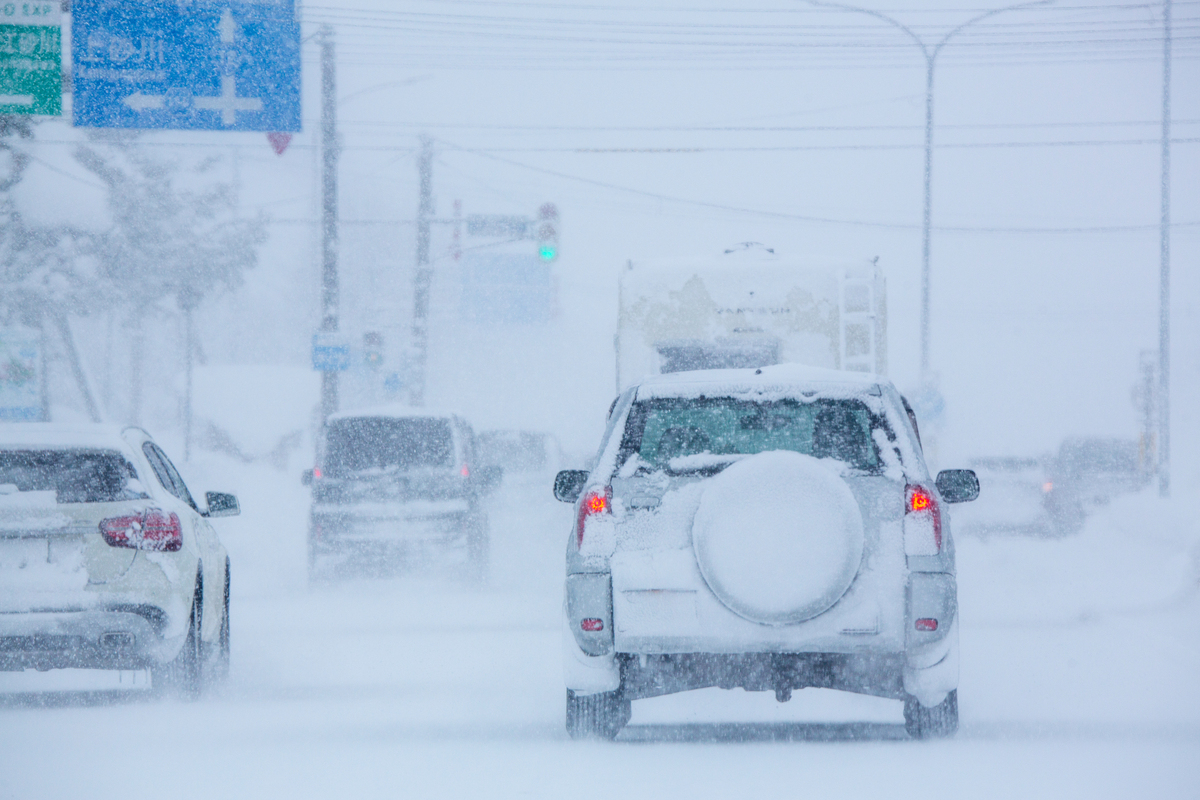 日本北海道冬季積雪道路上行駛的汽車