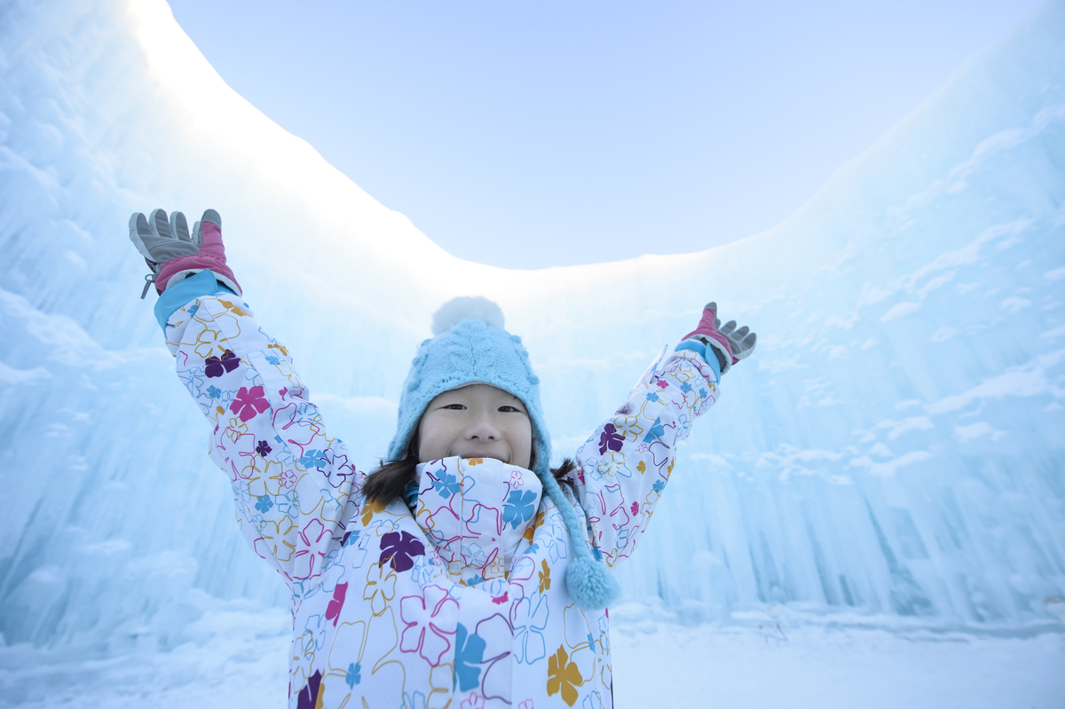 參加北海道雪祭的女孩站在冰雕前舉起雙手表示享受