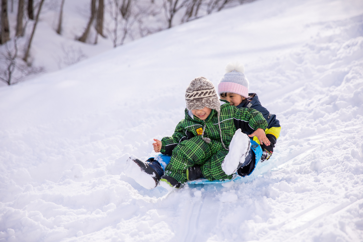 小孩在滑雪場旁玩雪橇